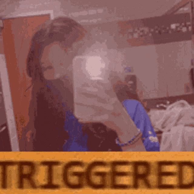 a woman is taking a selfie in front of a mirror with the word triggered in the foreground .