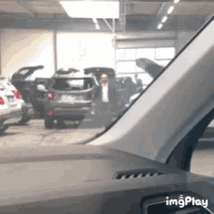a man in a suit is standing in a garage with his car open