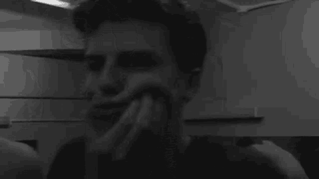 a black and white photo of two men making funny faces with their hands .