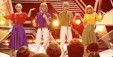 a group of women are singing into microphones on a stage