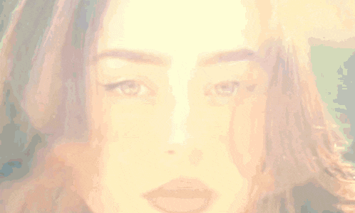 a woman with green eyes and red lips is looking at the camera .