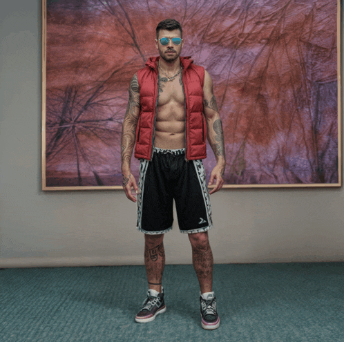a shirtless man wearing a red vest and black shorts