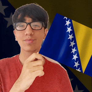 a man wearing glasses is holding a flag in front of a flag with stars on it
