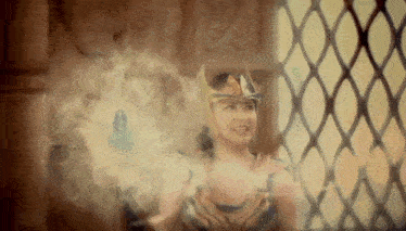a woman in a costume is standing in front of a window with smoke coming out of her hands .