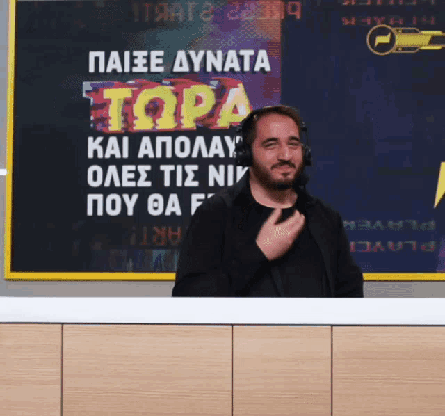 a man wearing headphones stands in front of a sign that says topia