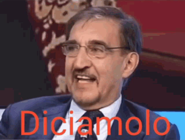 a man wearing glasses and a suit says " diciamolo "