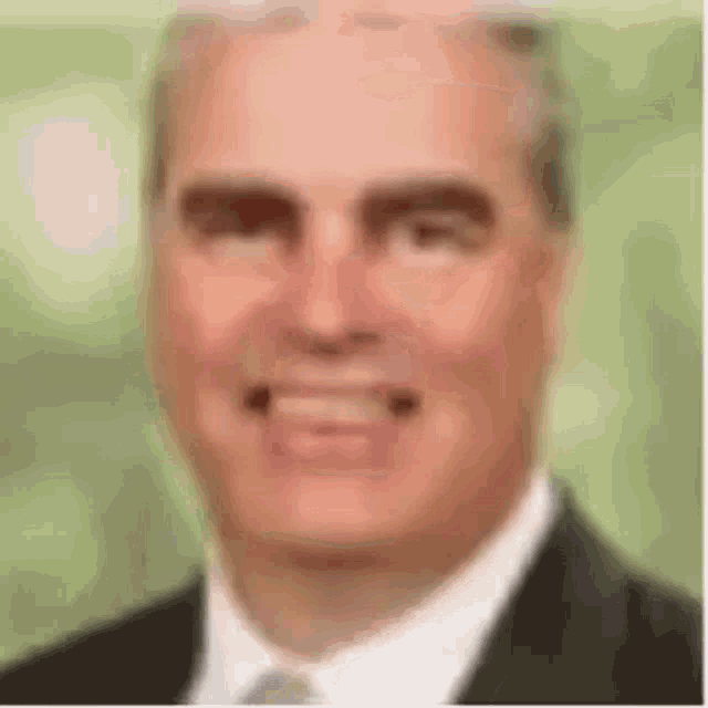 a man in a suit and tie is smiling and looking at the camera .