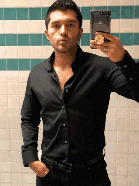 a man in a black shirt is taking a selfie with his iphone