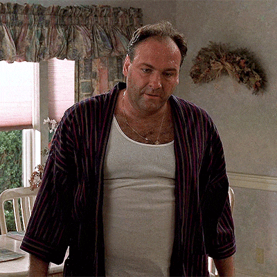a man wearing a striped robe and a white tank top is standing in front of a window