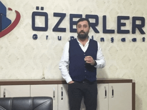 a man with a beard stands in front of a sign that says ozerler