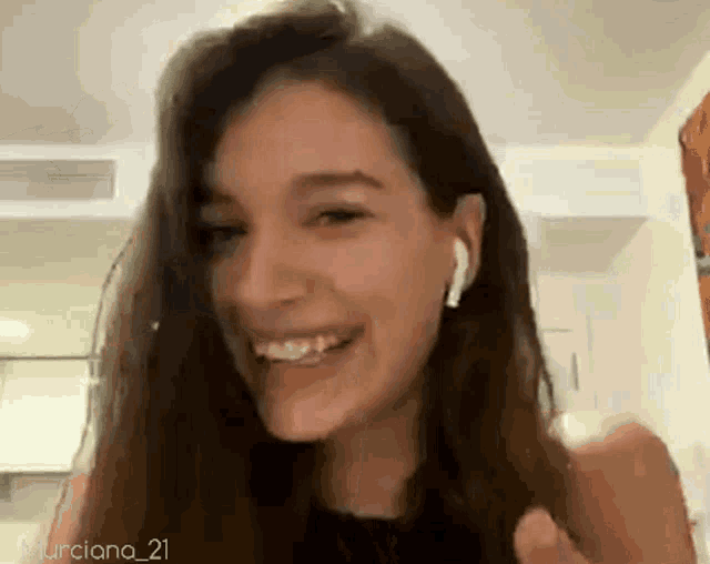 a woman wearing ear buds is smiling and giving a thumbs up .
