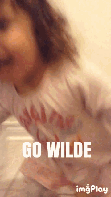 a little girl in a pink shirt with the words go wilde on it