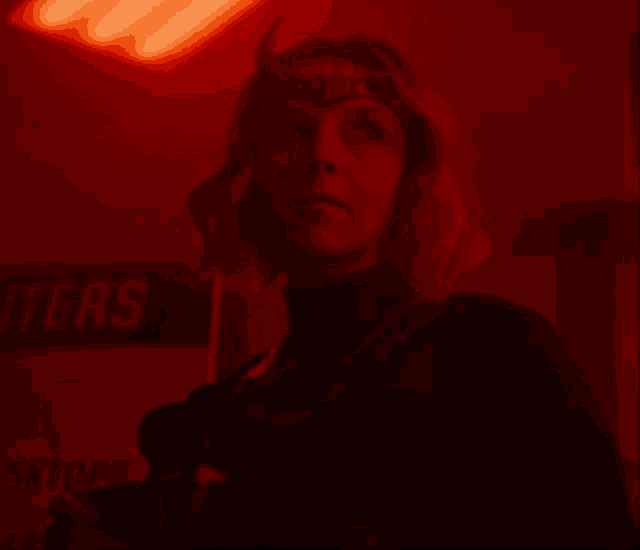 a woman is standing in a dark room with a red light behind her and a sign that says outer