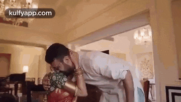 a man is carrying a woman on his shoulders in a living room and kissing her .