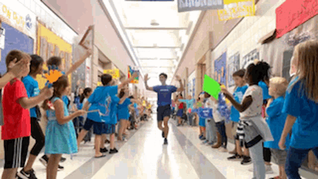 a group of children are standing in a hallway holding signs .