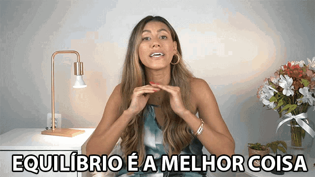 a woman is sitting in front of a table with flowers and the words equilibrio ea melhor coisa