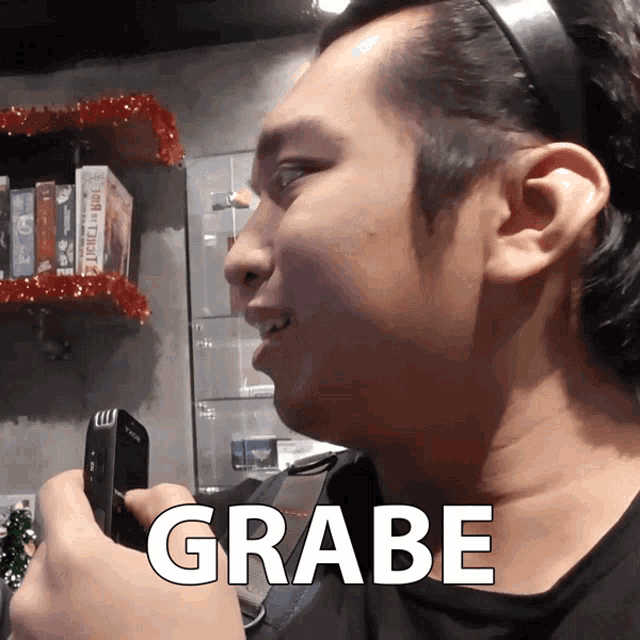 a man is holding a cell phone and the word grabe is on the bottom
