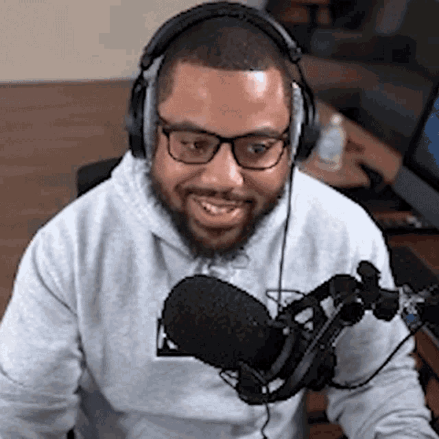 a man wearing headphones and a hoodie is sitting in front of a microphone .