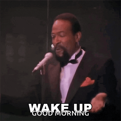 a man in a tuxedo singing into a microphone with the words wake up good morning written on the bottom