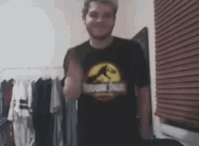 a man wearing a jurassic park t-shirt is standing in front of a closet .