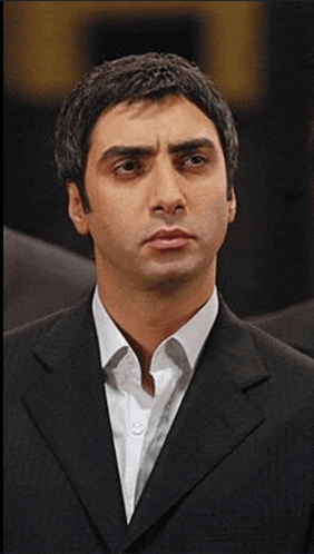 a man wearing a suit and white shirt looks at the camera