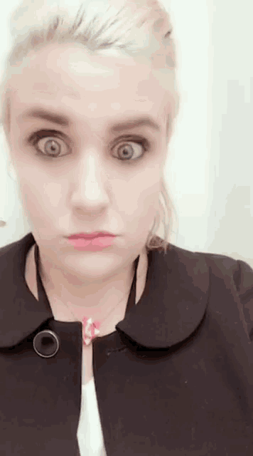 a woman is making a funny face with her eyes wide open .