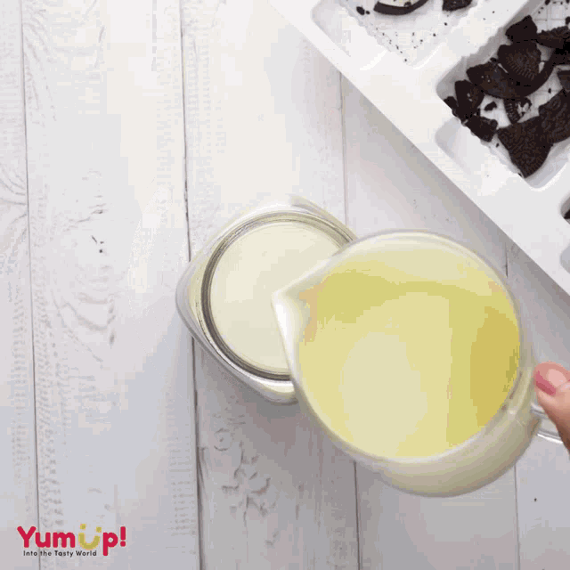 a person is pouring milk into a jar next to a container of oreos