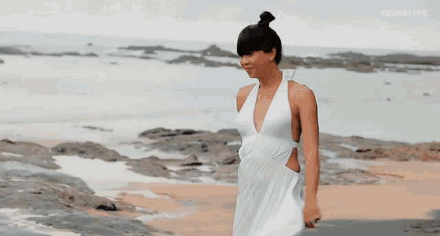 a woman in a white dress is standing on a rocky beach and the words yourstype are on the bottom