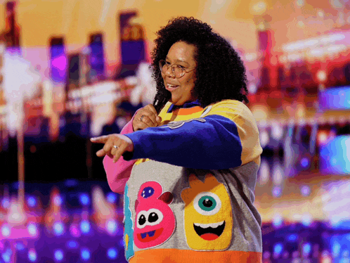 a woman wearing a colorful sweater with monster faces on it