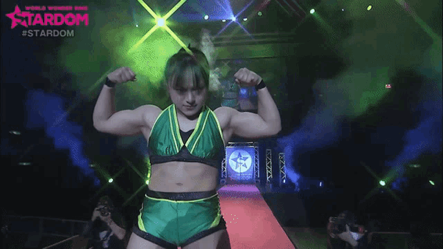 a woman in a green and yellow top is flexing her muscles in front of a stardom logo