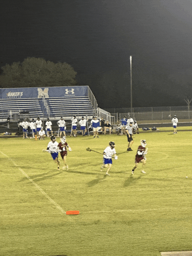 a lacrosse game being played in front of a baker 's field