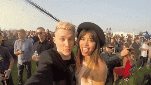 a man and a woman are posing for a selfie at a festival
