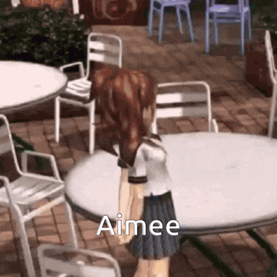 a girl in a school uniform is standing in front of a table and chairs with the word aimee written on it .