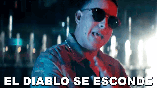 a man wearing sunglasses with the words el diablo se esconde behind him