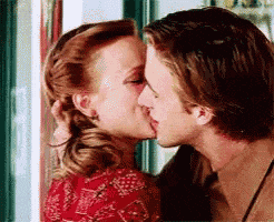 a man and a woman kissing in front of a window .