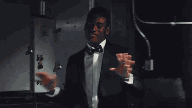 a man wearing a suit and bow tie is dancing