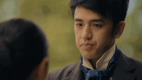 a man in a suit and tie looks at another person