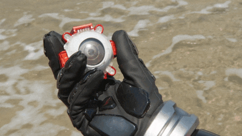 a person in a black glove is holding a silver object