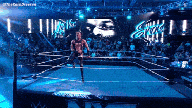 a wrestler in a wrestling ring with a large screen behind him that says ' evis '