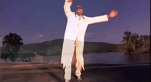 a man in a white coat and hat is dancing in front of a lake .