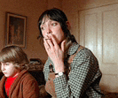 a woman is covering her mouth with her hand while a boy sits next to her .