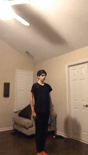 a man in a black shirt stands in a living room