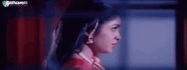 a woman in a red dress is standing in a dark room looking at something .