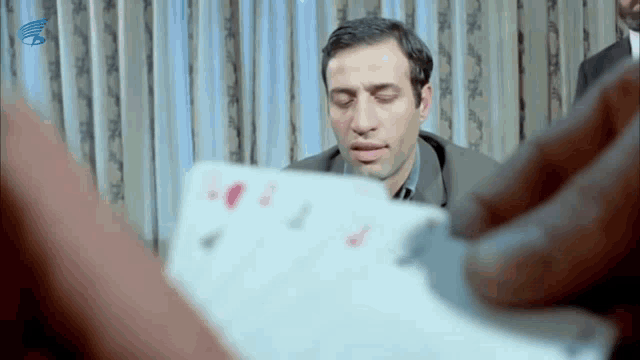 a man is holding a piece of paper with playing cards on it in front of him .