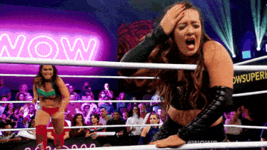 a woman in a wrestling ring with a neon sign that says now