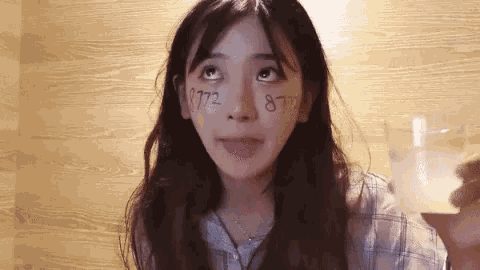 a woman with numbers written on her face looks up at the sky