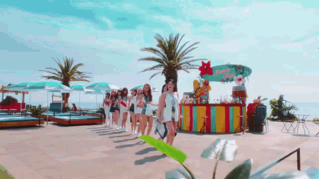 a group of women are standing in front of a colorful bar on a beach