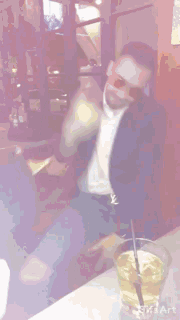 a man sits at a table with a glass of beer and a gifs art watermark
