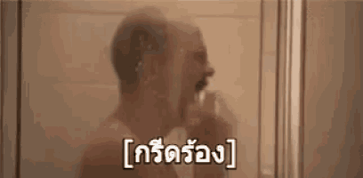 a man is taking a shower in a bathroom with a foreign language written on it .