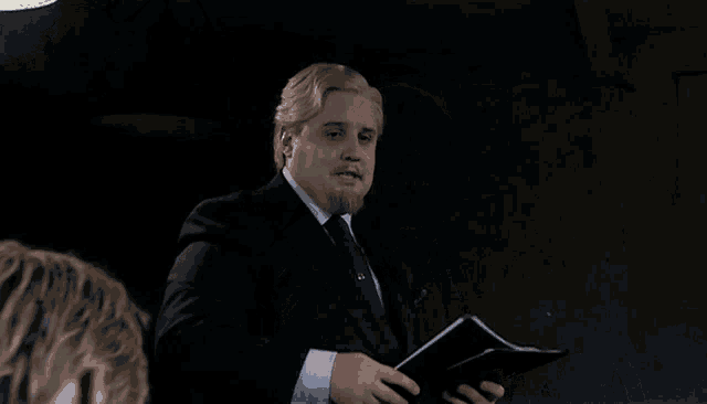 a man in a suit and tie is shaking hands with a woman in a dark room .